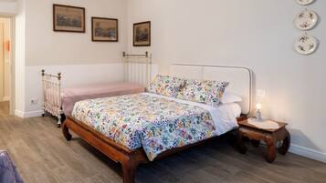 Un dormitorio con una cama de madera, una mesita de noche con una lámpara, y tres cuadros enmarcados en la pared.