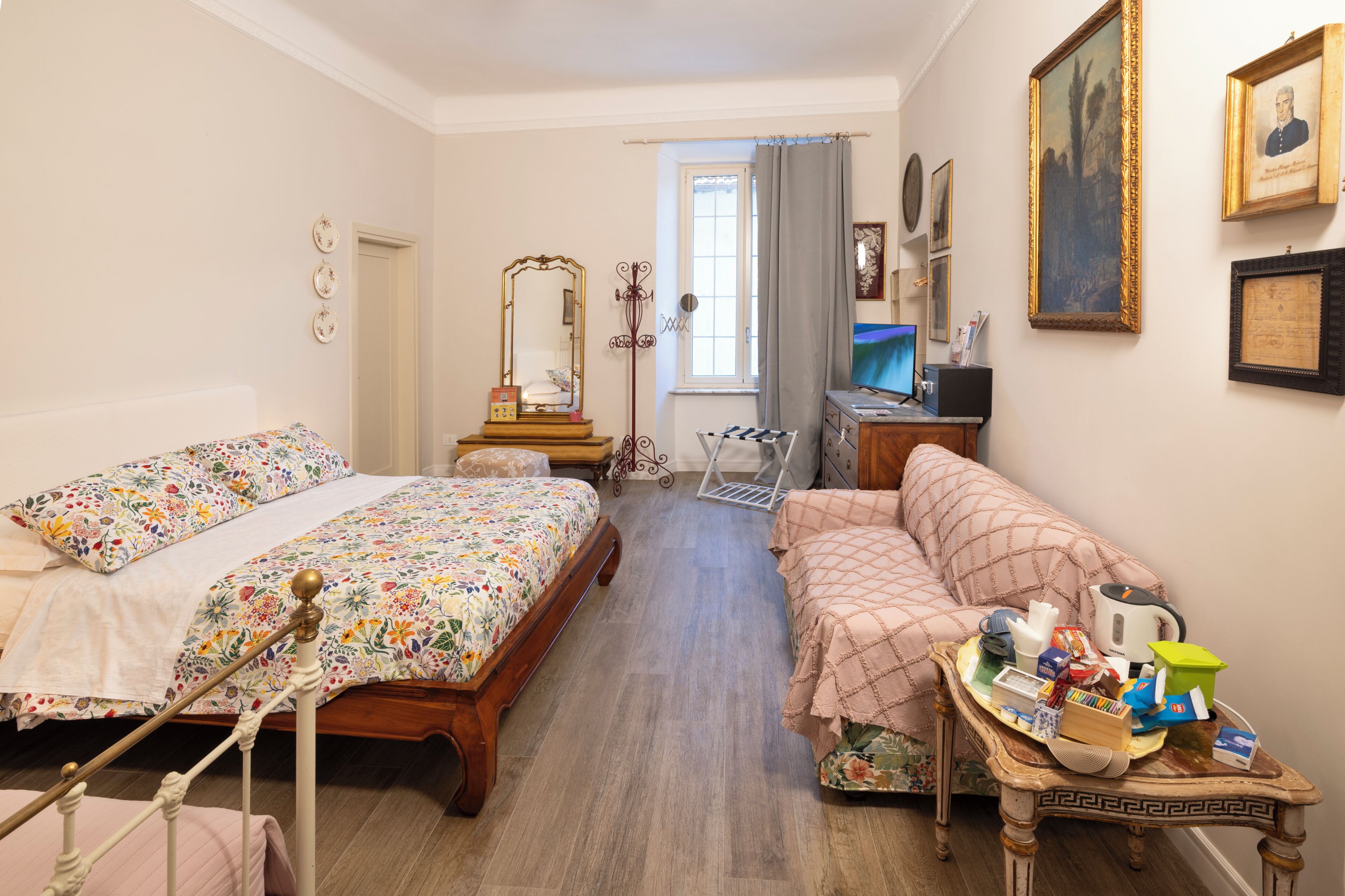 A bedroom with two beds, a desk, a chair, and a small table with various items.