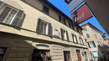 Un edificio con varias ventanas, algunas con contraventanas, y un letrero sobre la entrada.