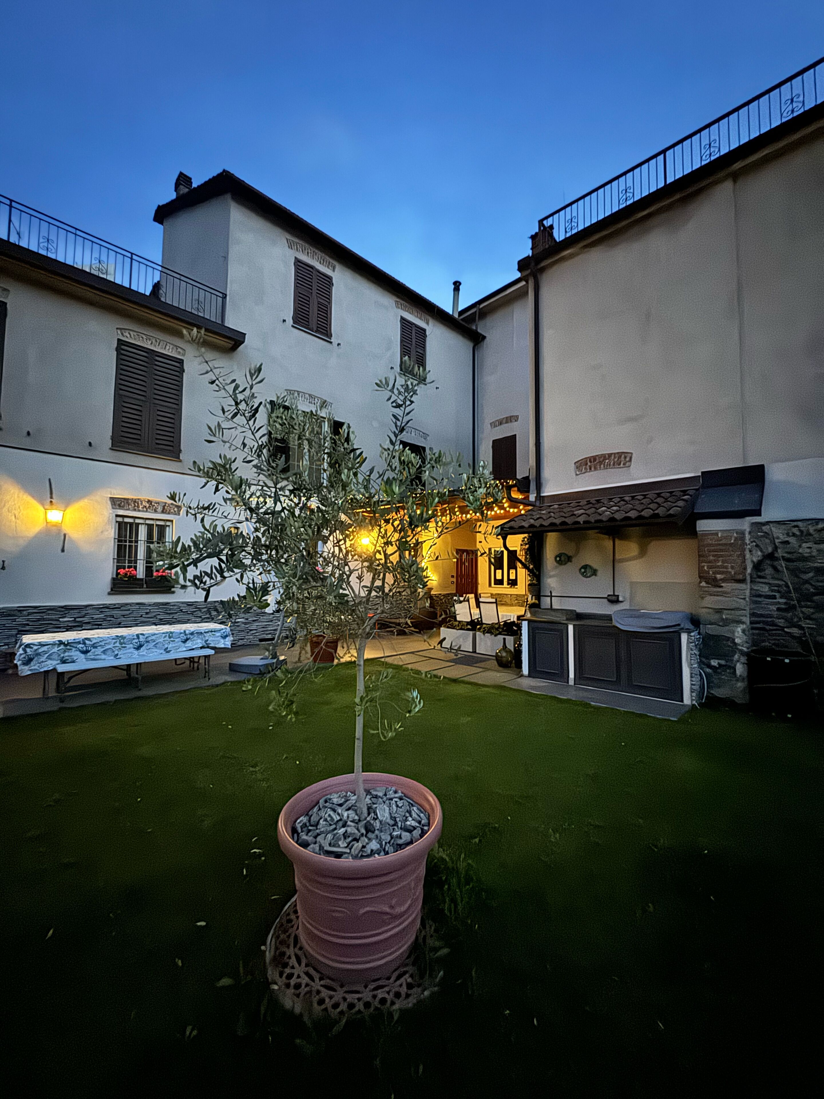 Un patio con un árbol pequeño, una mesa con mantel y un edificio con balcón.