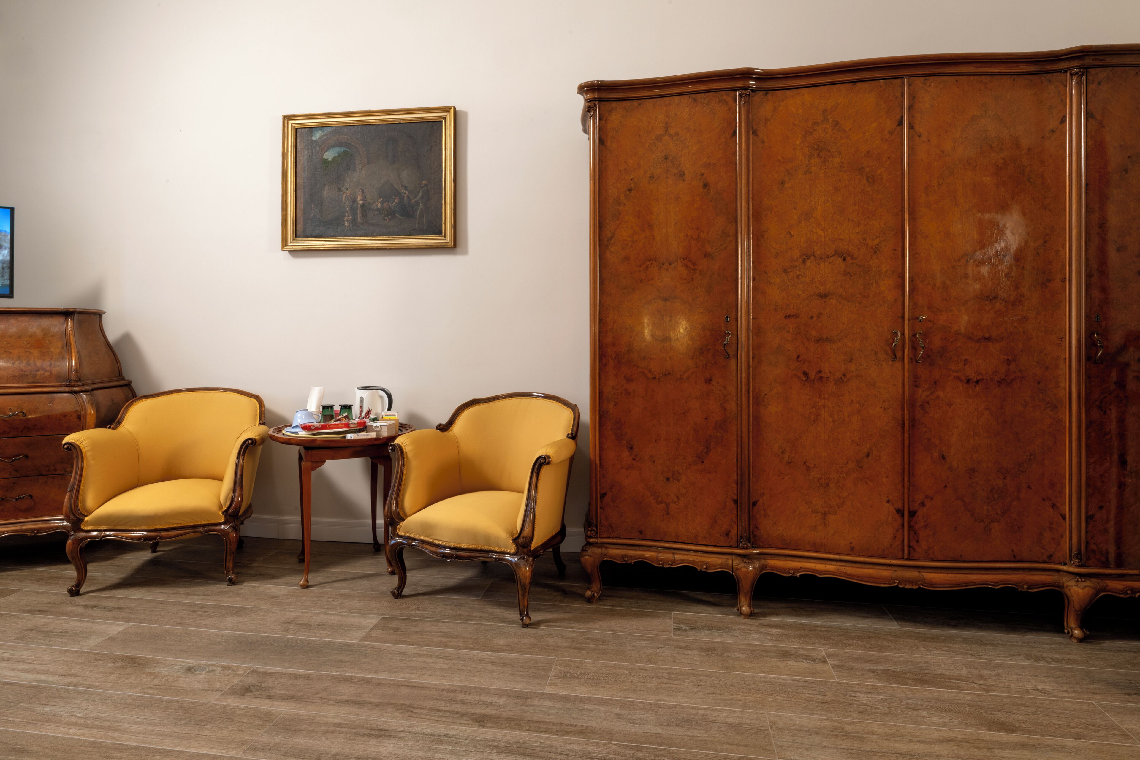 Una habitación con dos sillones amarillos, un aparador de madera y una mesita con objetos encima.