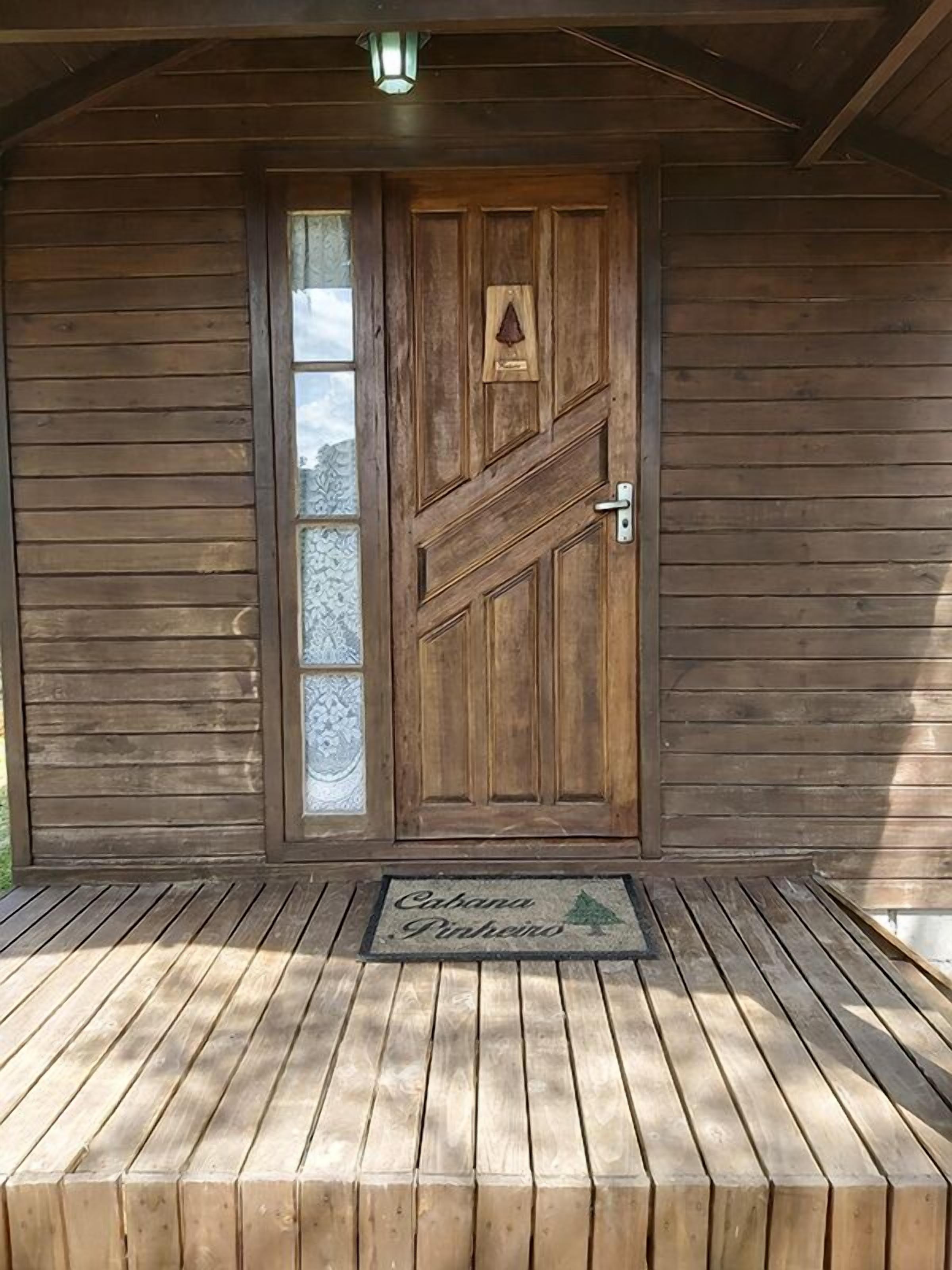 A wooden door with a glass panel and a metal handle, set in a wooden structure with a metal roof.