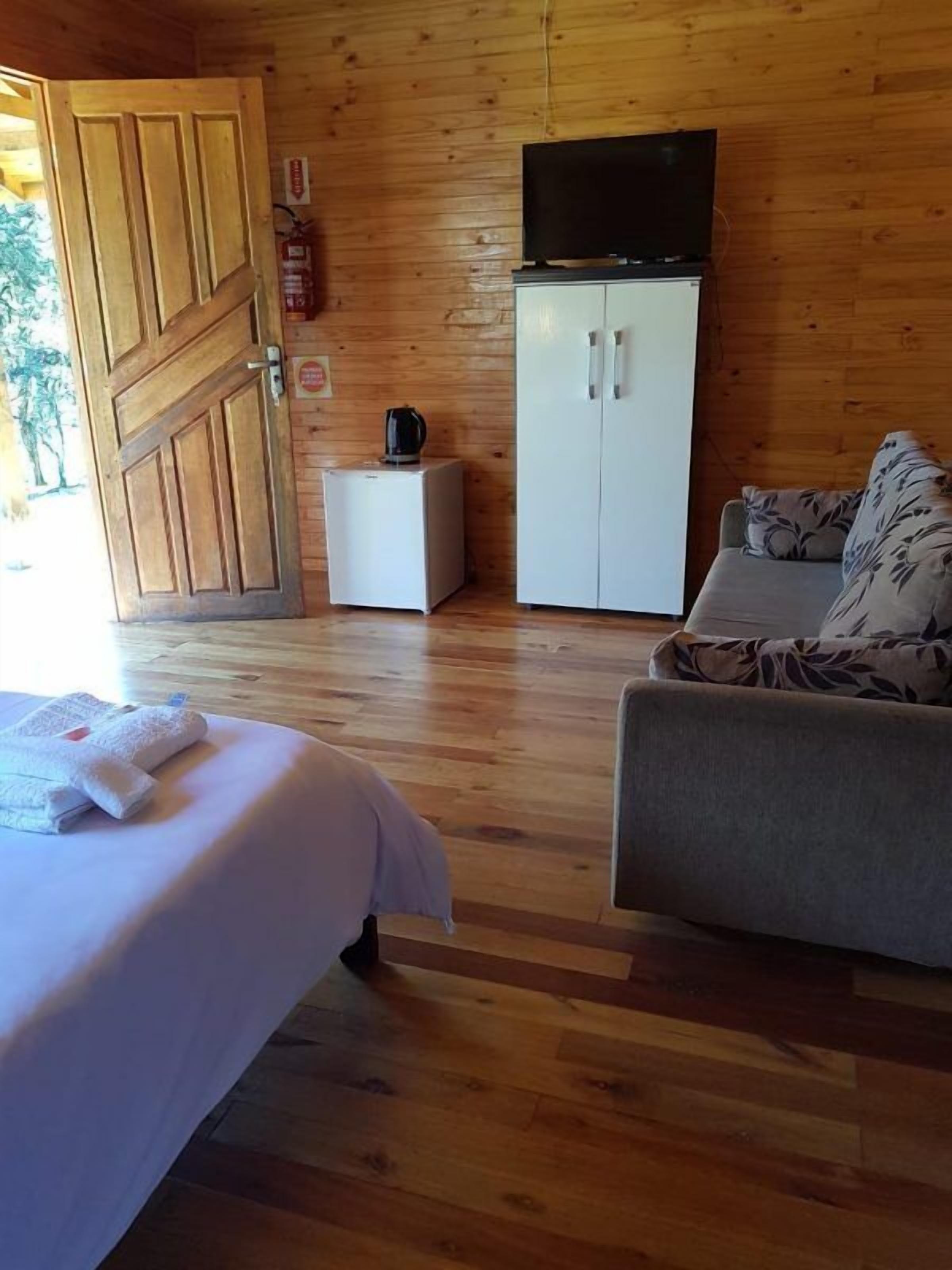 Una habitación con paneles de madera, una cama, un sof á, un armario y una televisión.