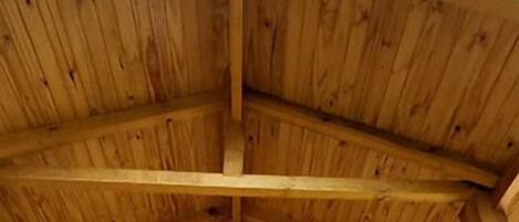 Una cabaña de madera con techo inclinado, una puerta de madera con ventana y una terraza de madera.