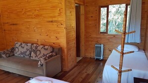 Une pièce de chalet en bois comprenant un canapé, un lit et un radiateur.