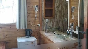 Une salle de bain rustique, avec une cabine en bois, un meuble-lavabo en bois, un lavabo en verre et un miroir.
