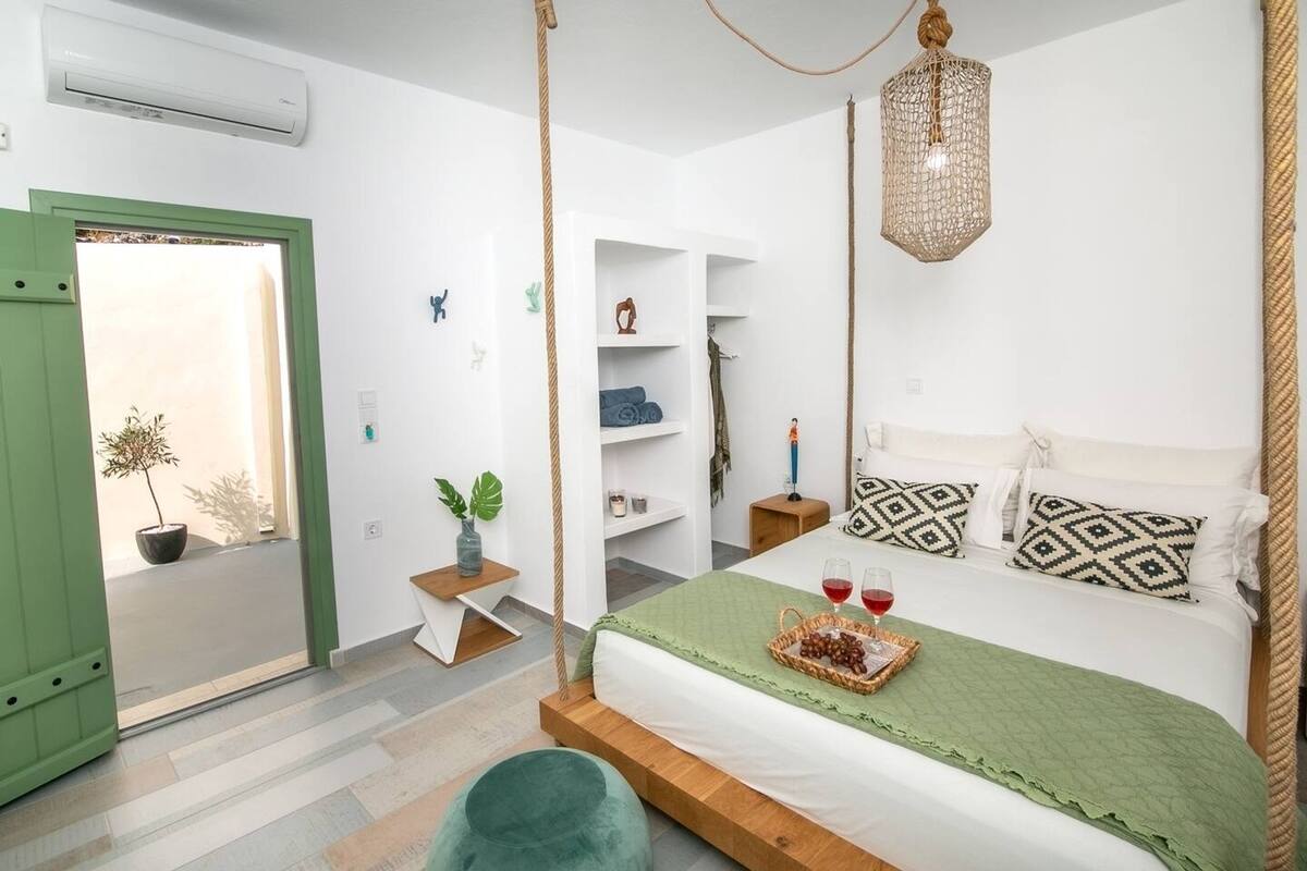 A bedroom with a bed, bedside table, hanging light, and a green door.