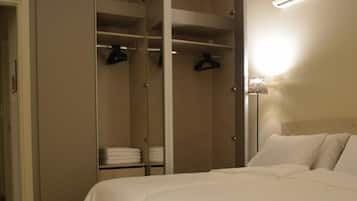 A bedroom with a bed, a walk-in closet, and a wall-mounted heater.