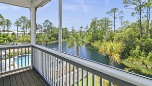 A covered balcony with a view of a lake and surrounding trees. - 3,000+ Sq Ft! Golf Cart & 6 Bikes! Walk to 2 Pools! 3 King Suites and Bunk Room! ~ Unwined at Naturewalk on 30A (Santa Rosa Beach)