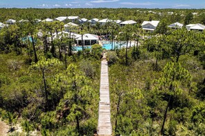 A resort with a central pool, surrounded by dense forest and multiple buildings with white roofs. - 3,000+ Sq Ft! Golf Cart & 6 Bikes! Walk to 2 Pools! 3 King Suites and Bunk Room! ~ Unwined at Naturewalk on 30A (Santa Rosa Beach)