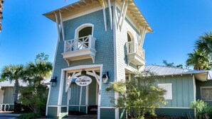 A two-story building with a balcony, a sign reading "The Gathering Place," and a number "25" on the side. - 3,000+ Sq Ft! Golf Cart & 6 Bikes! Walk to 2 Pools! 3 King Suites and Bunk Room! ~ Unwined at Naturewalk on 30A (Santa Rosa Beach)