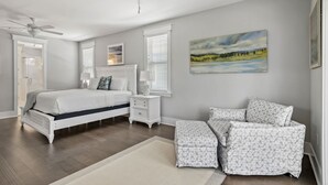 A bedroom with a bed, nightstands, a chair, a painting, and a ceiling fan. - 3,000+ Sq Ft! Golf Cart & 6 Bikes! Walk to 2 Pools! 3 King Suites and Bunk Room! ~ Unwined at Naturewalk on 30A (Santa Rosa Beach)
