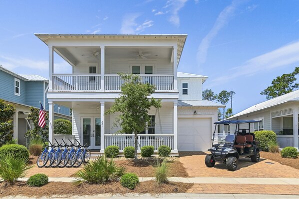 A two-story building with a balcony, a garage, and a golf cart parked in front.
