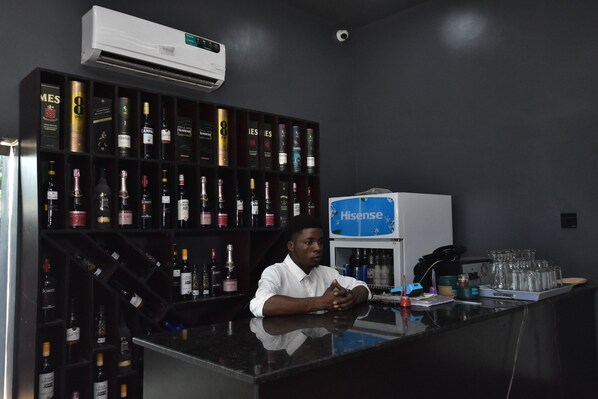 A bar area with a man seated at the counter, surrounded by shelves of liquor bottles.