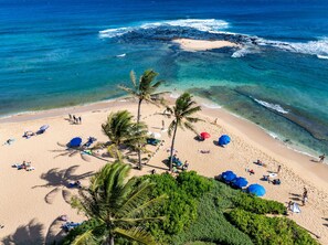 A beach with clear turquoise water, palm trees, and people sunbathing. - New Listing 4 bedroom steps from Poipu beach AC hottub (Koloa)
