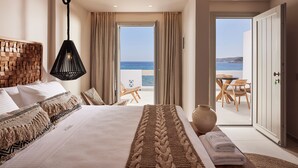 Una camera da letto con un letto grande, vista sul mare e un balcone con sedie.
