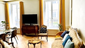 Una sala de estar con sofá, sillas, una mesa de centro, televisor y un comedor con mesa y sillas.