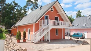 Ein zweistöckiges Haus mit Balkon und Auffahrt, auf der ein Van geparkt ist.
