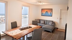 Ein modernes Wohnzimmer mit einem Holzesstisch, einem grauen Sofa und einem Bild eines Piers.