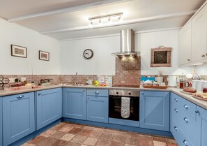 Kitchen features a stainless steel range hood, oven, and sink with faucet, along with a central island and various kitchen items.