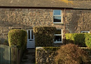 Traditional stone house with a symmetrical facade and well-mainters hedges.