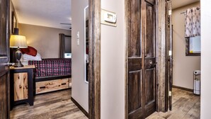 Un dormitorio con cama, mesita de noche, lámpara y un termostato en la pared.