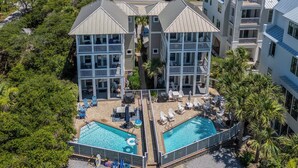A two-story building with a swimming pool and outdoor seating area. - Private Beach! Gulf Views! Heated Pool! (Seacrest)