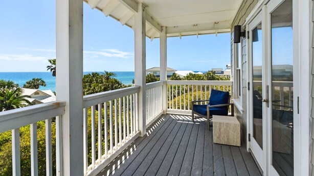 A covered balcony with a view of the ocean, a chair, and a small table. - Private Beach! Gulf Views! Heated Pool! (Seacrest)