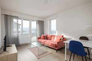 Relax in this stylish living room with a city view, featuring a comfortable sofa, dining area, and flat-screen TV.