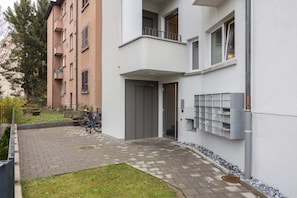 Stylish residential building with balconies and a flat facade, featuring a garden area and bike parking.