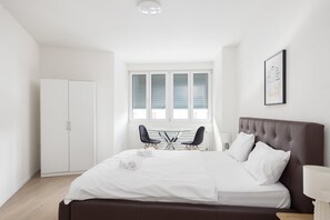 Relax in a spacious room with a large bed, a small table, and a wardrobe.