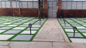 A courtyard with a paved pathway, a brick wall, and two lamp posts. - Ojong's Guesthouse (Cape Town)