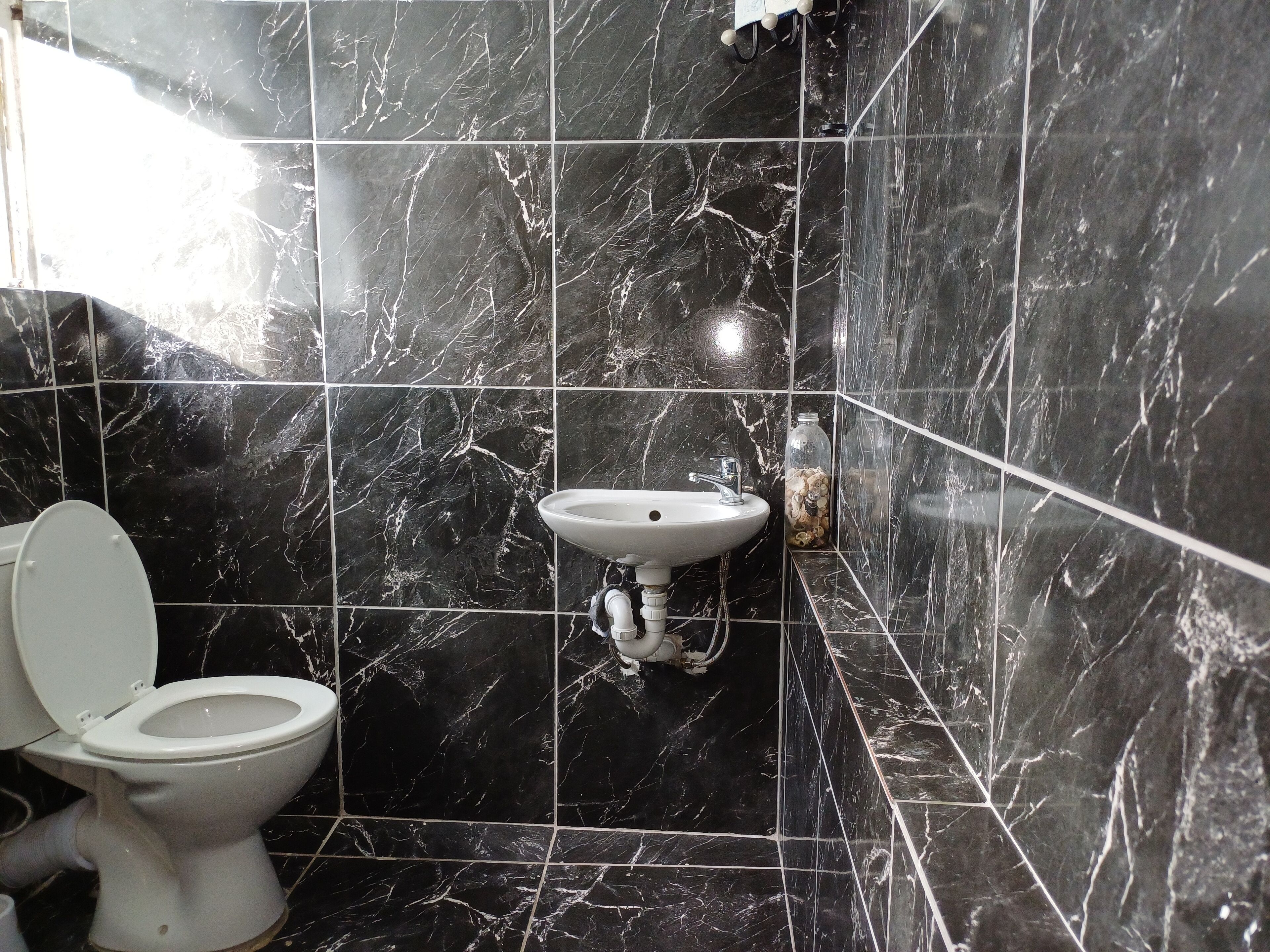 A bathroom with black marble tiles, a white toilet, and a white sink.