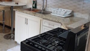 A kitchen with white cabinets, a granite countertop, a stainless steel sink, and a black stove.