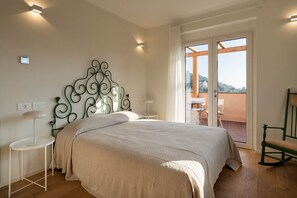 Une chambre à coucher comprenant un lit, une table de chevet, une chaise et une vue sur l’extérieur grâce à une porte-fenêtre coulissante.