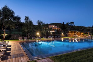 Une piscine avec des chaises longues et un mur en pierre.