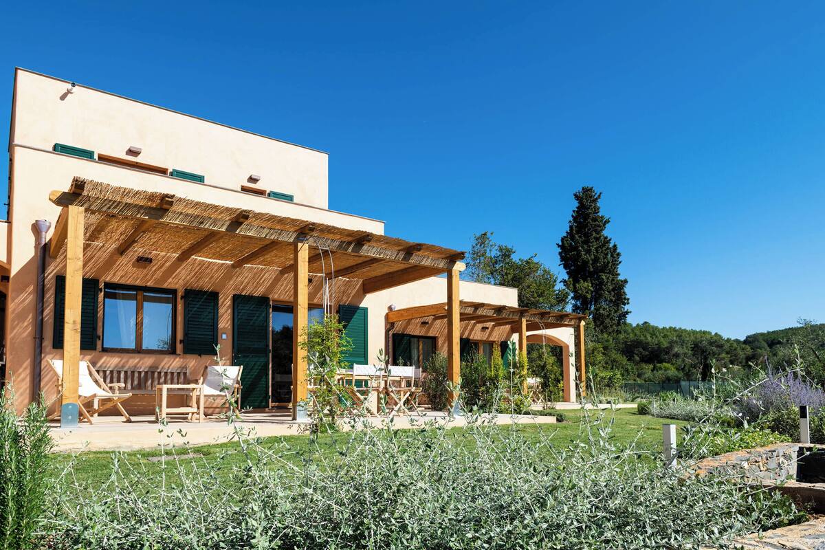 A modern house with a covered patio, outdoor seating, and a well-maintained garden.