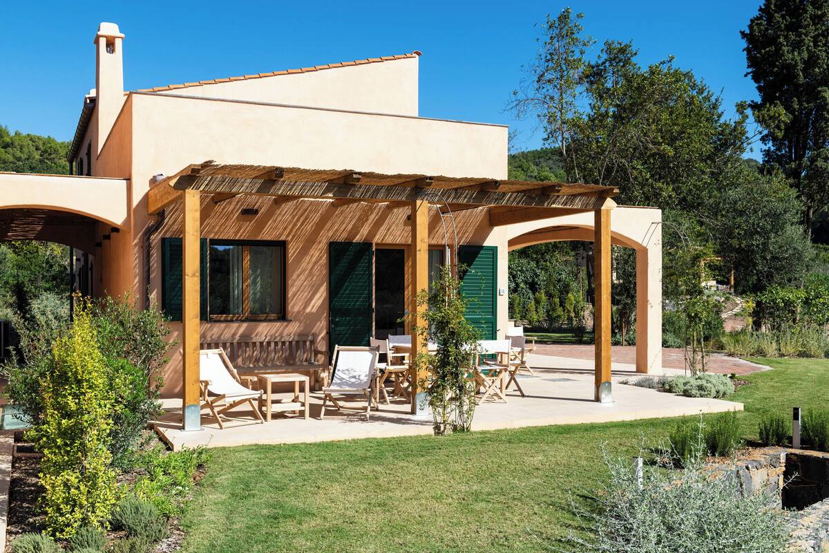 A modern house with a covered patio, outdoor seating, and a well-maintained garden.