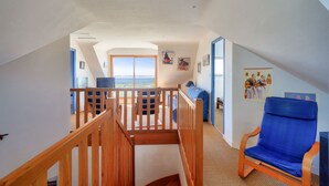 A spacious room with a wooden staircase, a blue chair, and a large window offering a view. - Sea view, 200m from the beach, house for 9 (Plovan)
