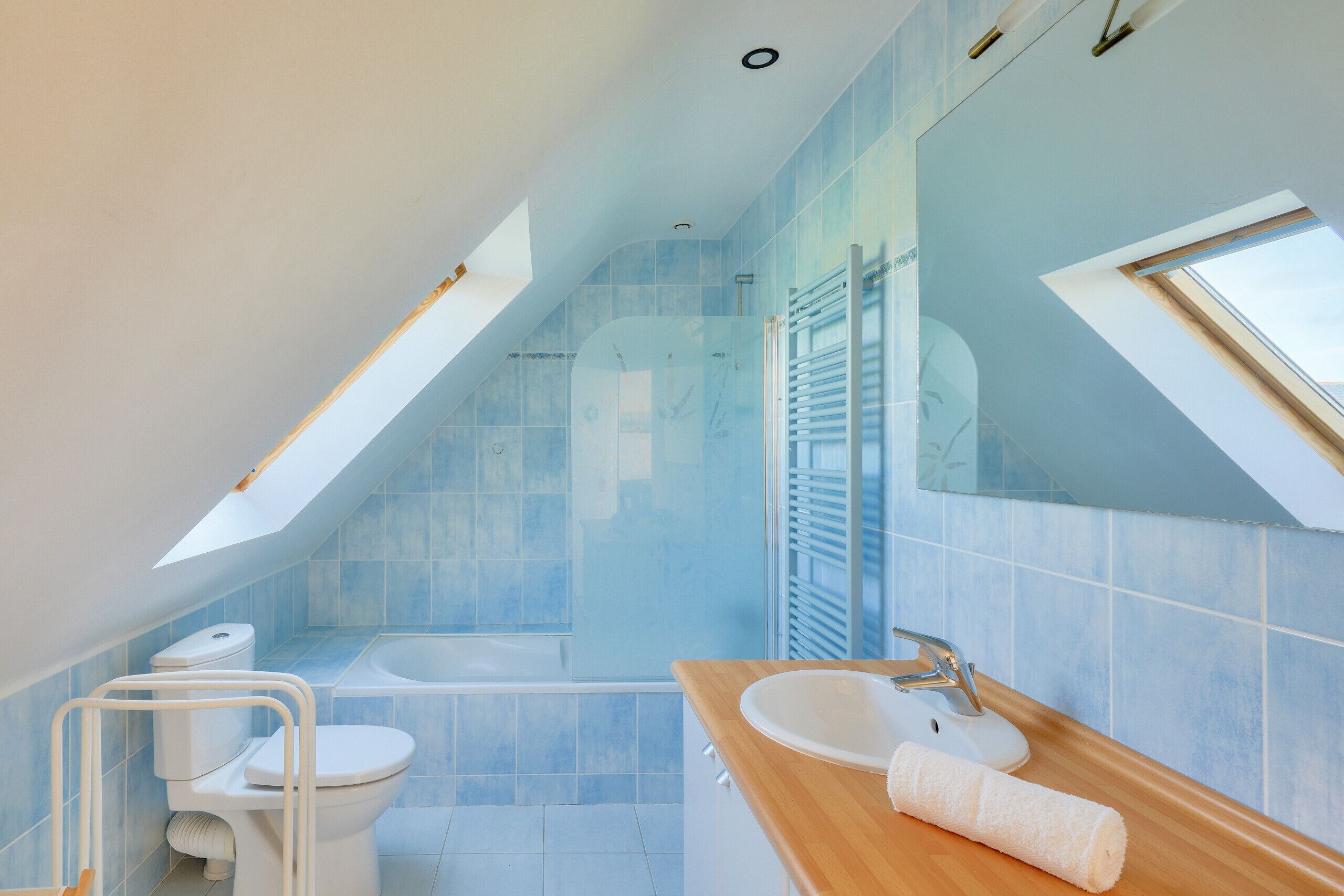 Une salle de bain moderne avec un puits de lumière, une baignoire, des toilettes et un lavabo.
