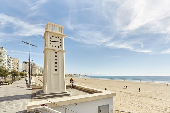 Stunning coastal views of a clock tower overlooking a vast sandy beach.