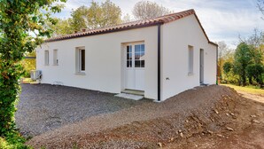 A single-story building with a tiled roof, a gravel driveway, and a small front porch. - Saint-Vincent-sur-Jard, house for 5 (Saint-Vincent-sur-Jard)