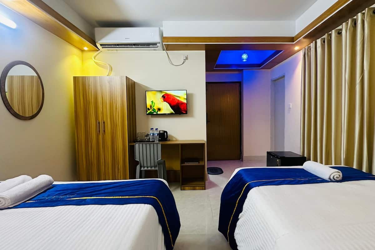 A hotel room with two beds, a desk, a mirror, and a TV.