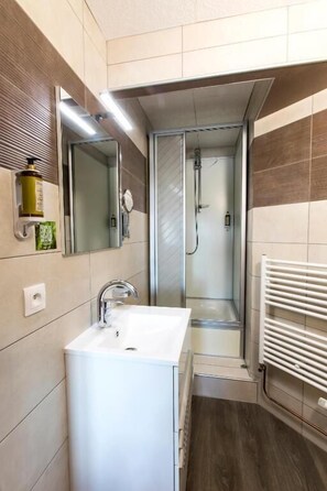 Une salle de bain moderne avec un lavabo blanc, un miroir et une douche à parois de verre.