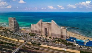 Un grand hôtel doté d’une cour intérieure, entouré d’un parking et situé à proximité d’une plage.