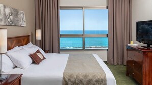 Une chambre d’hôtel avec un grand lit, une télévision, un bureau et une vue sur l’océan.