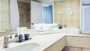 Un baño moderno con un espejo grande, un lavamanos con tocador, un inodoro y una zona de ducha.
