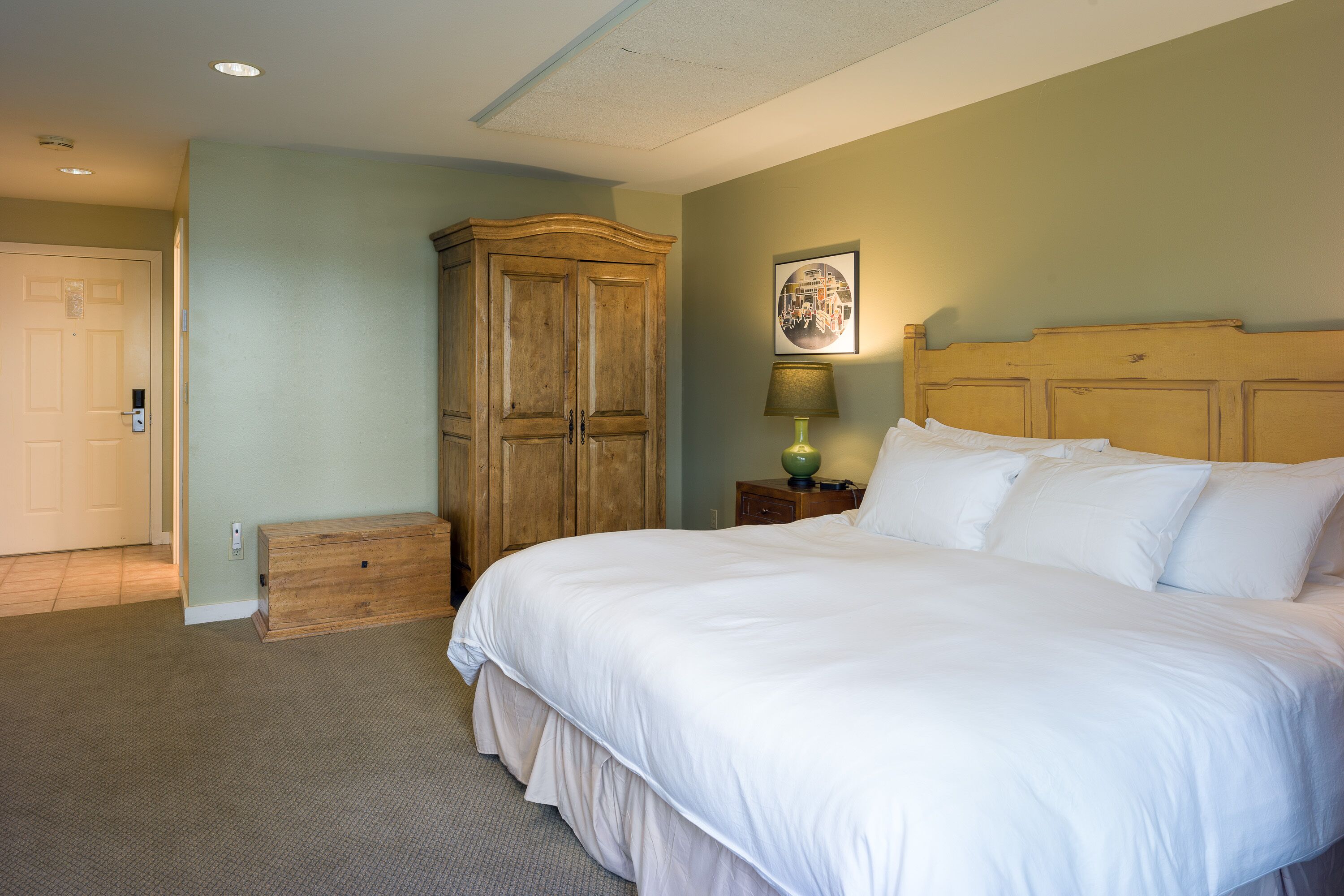 Une chambre à coucher avec un grand lit, une armoire en bois et une table de chevet avec une lampe.