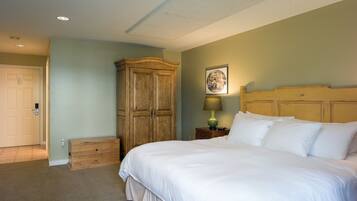 A bedroom with a large bed, wooden wardrobe, and a nightstand with a lamp.