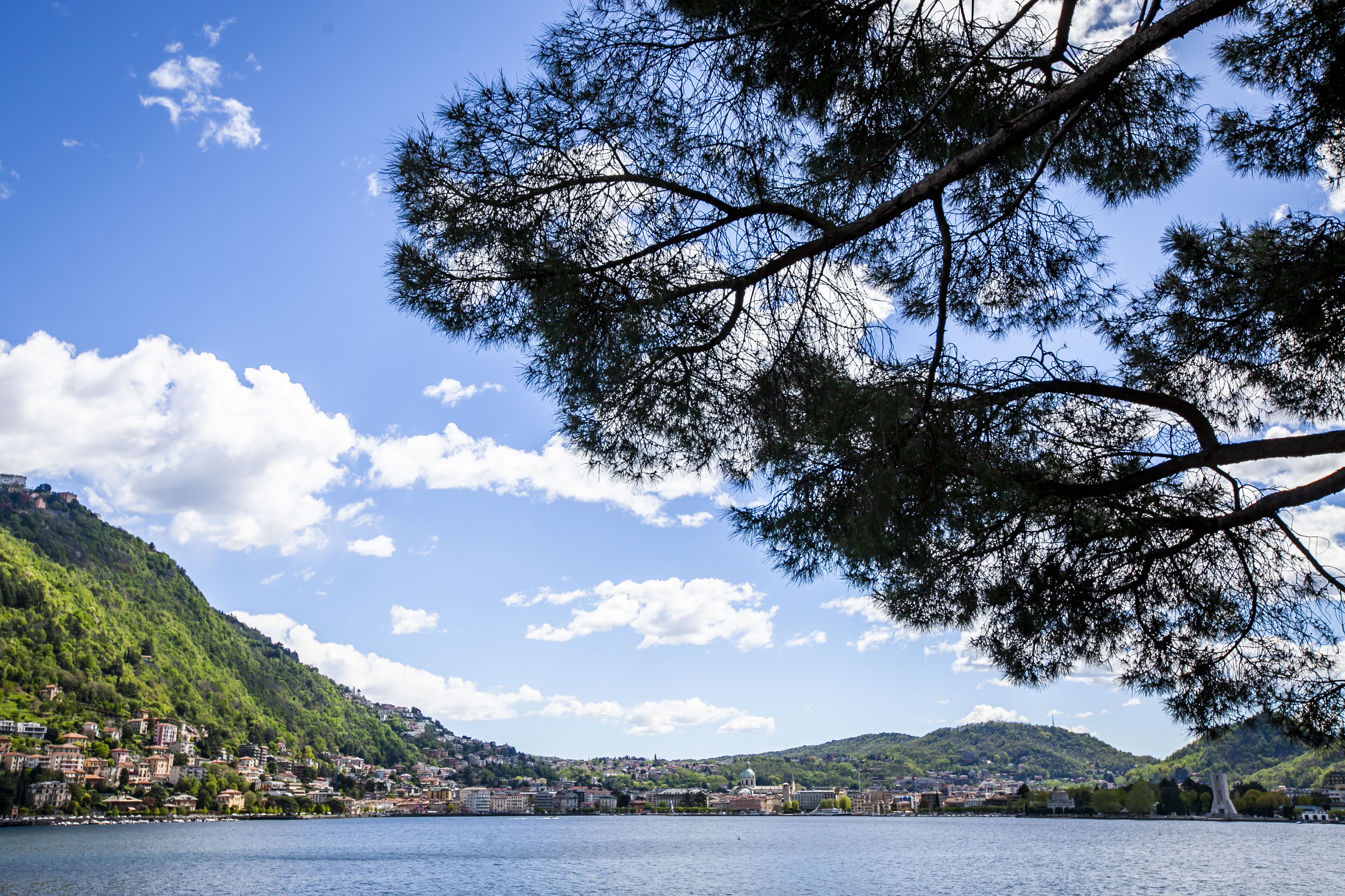 A lakeside town with buildings on a hillside, a bridge, and a clear sky.